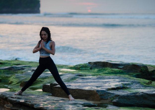 Girl doing yoga during sunset on the beach
