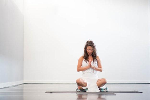 girl sitting on yoga mat in white room