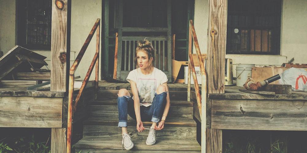girl sitting in front of abandoned house