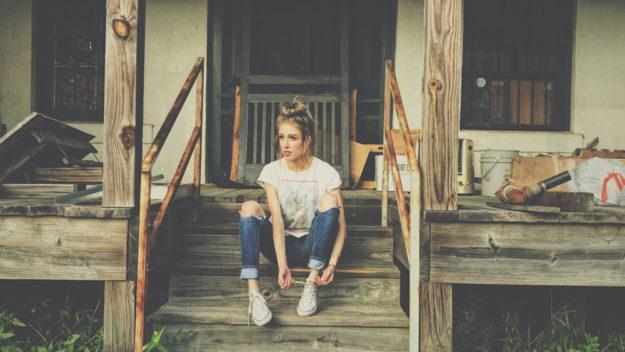 girl sitting in front of abandoned house
