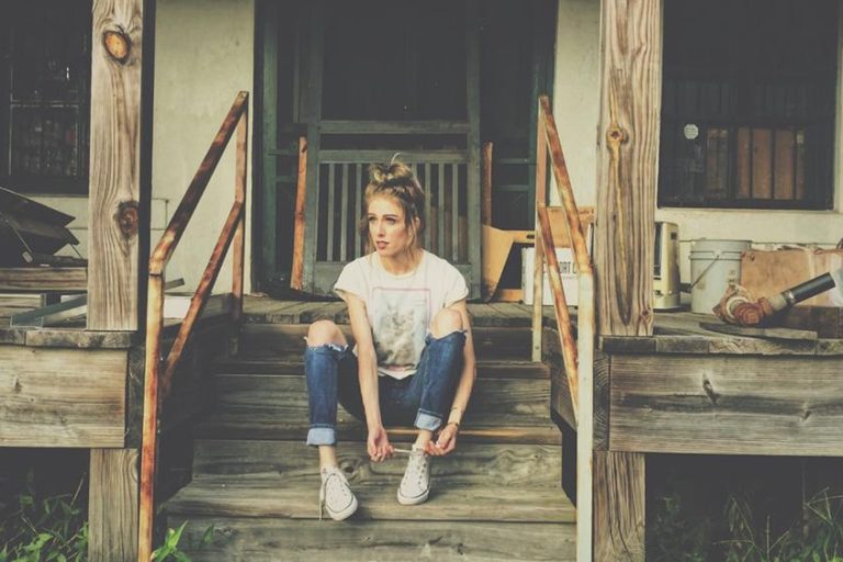 girl sitting in front of abandoned house