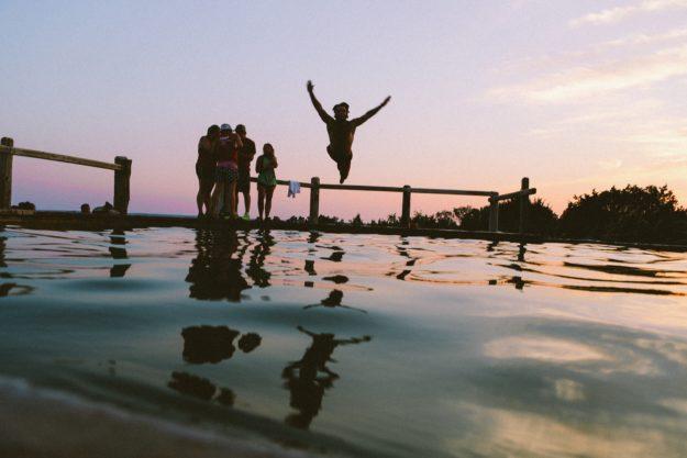 summer-in sobriety man jumping into the ocean with group of friends