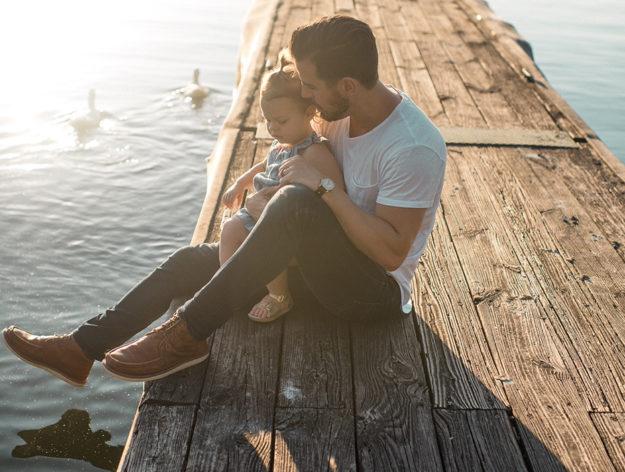 Man holding his daughter on a dock