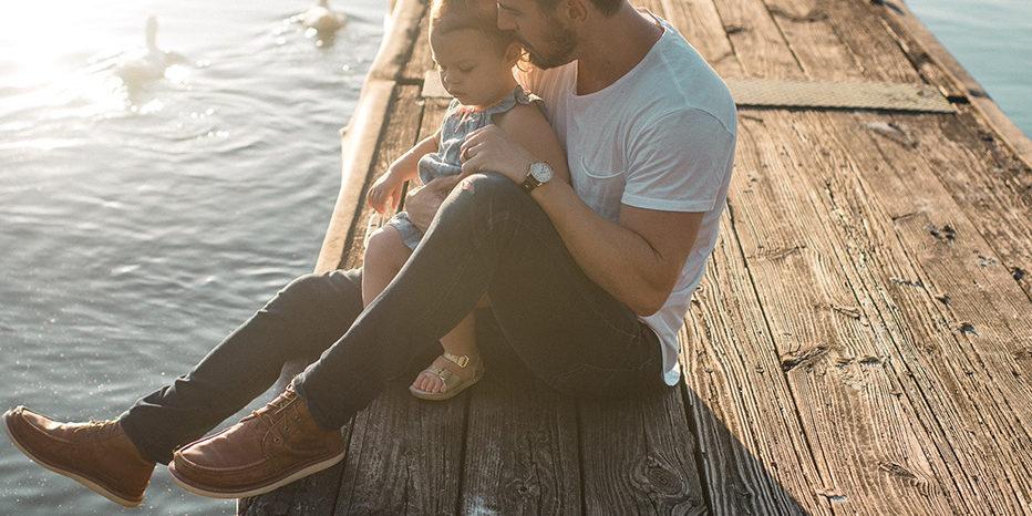 Man holding his daughter on a dock