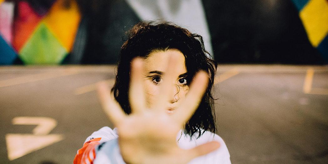 girl with black hair looking up with her hand inront of camera