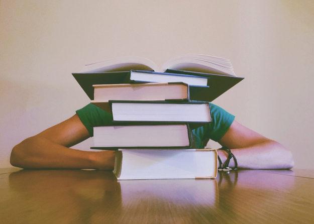 girl with her head in stacked books