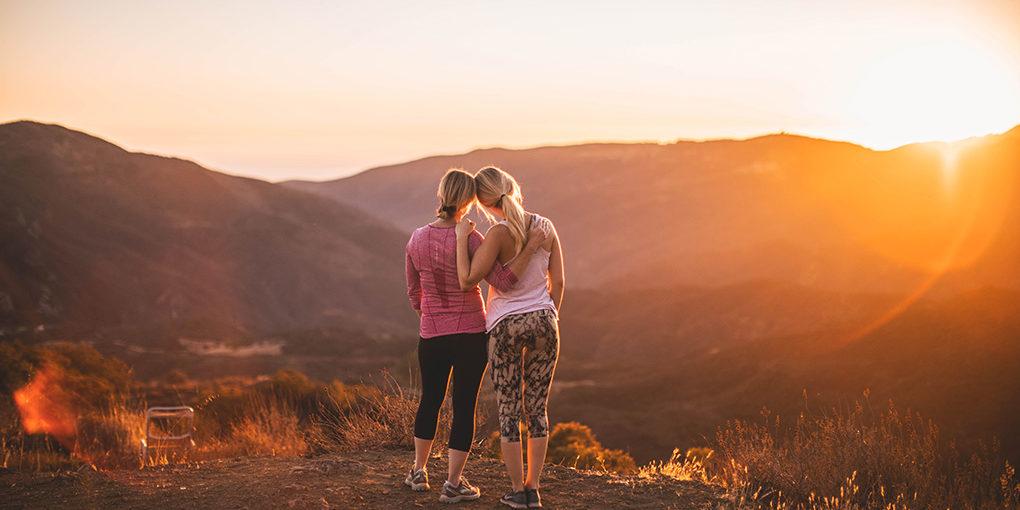 two girls hugging on hike during sunset