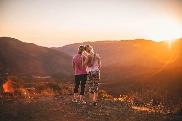 two girls hugging on hike during sunset