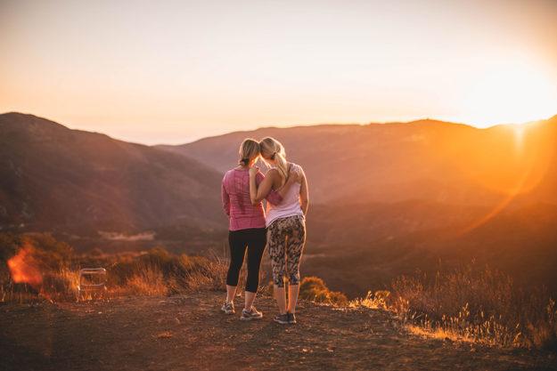 help two girls hugging on hike during sunset