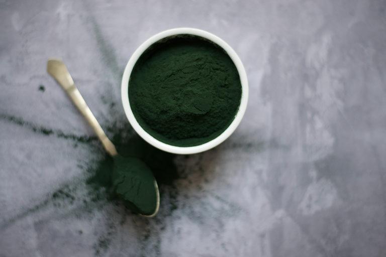 green kratom powder in cup with spoon